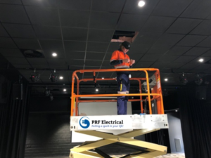 PRF Electrical expert electrician installing led lighting panels in a school hall